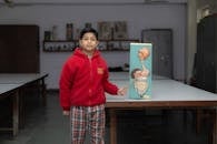 A young student in a classroom presenting an anatomical model, showcasing educational focus.